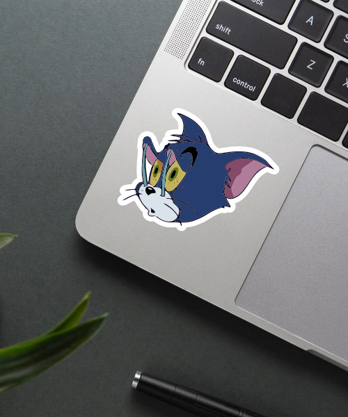 sleepy tom cartoon sticker on laptop surface showing tired cat face
