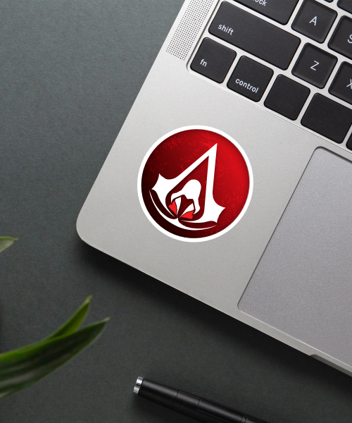 Assassins Creed sticker on a laptop surface.