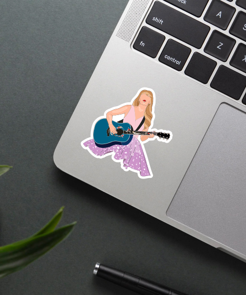taylor swift guitar sticker on laptop surface showing purple dress and blue guitar