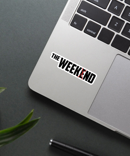 the weeknd name sticker on laptop surface showing bold black text with red cross design