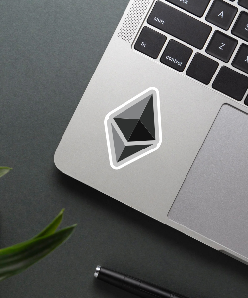 ethereum logo sticker on laptop surface showing black and grey crypto symbol