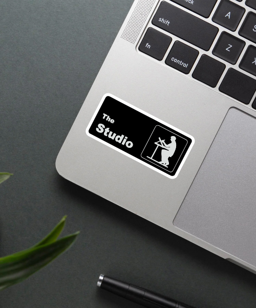 the studio sticker with black background and white silhouette on laptop surface