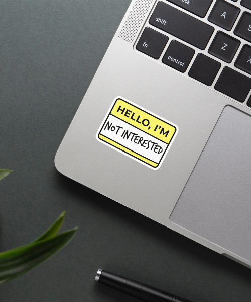 hello i'm not interested sticker on laptop showing yellow name tag style with bold text