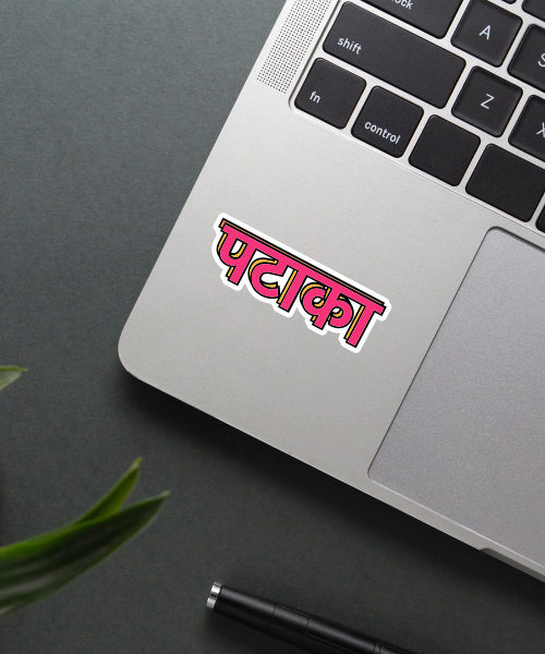 pataka sticker on laptop surface showing bright pink Hindi text with bold outlines