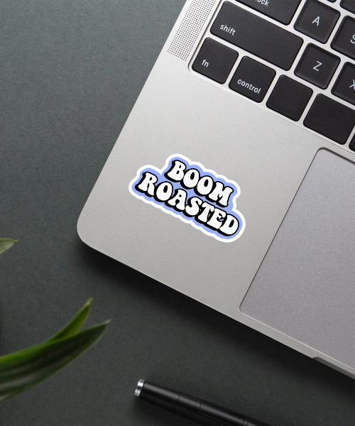 boom roasted sticker on laptop surface showing bold white text on blue background
