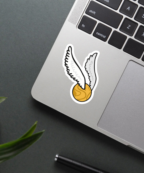golden snitch sticker on laptop surface showing gold ball and white wings