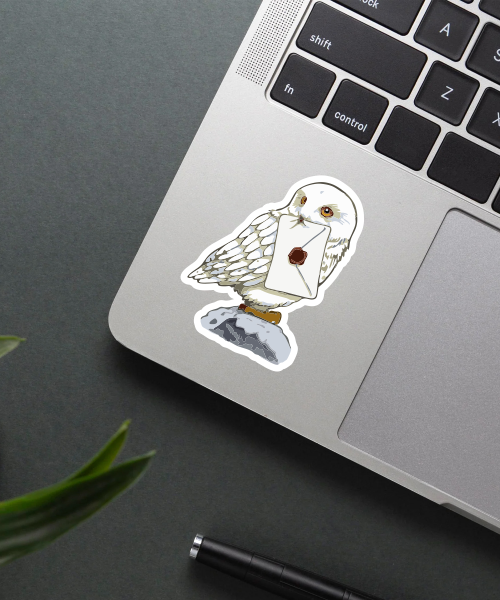 cute hedwig sticker on laptop surface showing white owl holding letter
