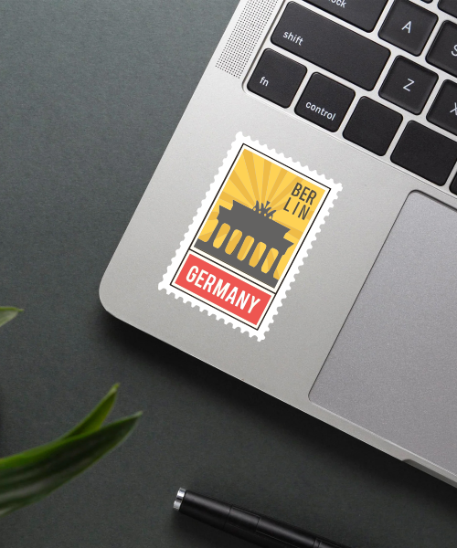 Mockup showing Berlin Germany travel sticker on laptop with Brandenburg Gate yellow red design.