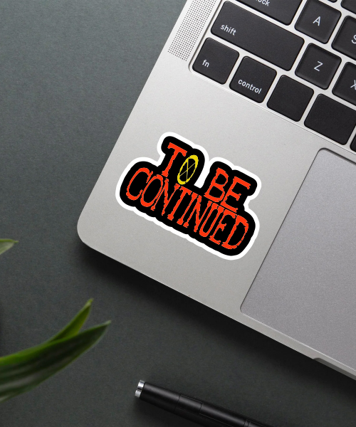 One Piece To Be Continued vinyl sticker applied on a laptop surface showing bright orange text