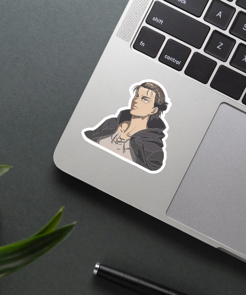 Eren Attack On Titan vinyl sticker on laptop showing character with dark cloak and serious look