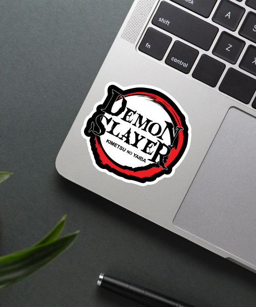 demon slayer logo sticker on laptop surface showing red circle and black text