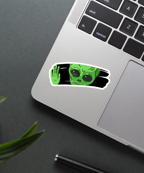 Alien Behind Glass Sticker on a laptop surface.